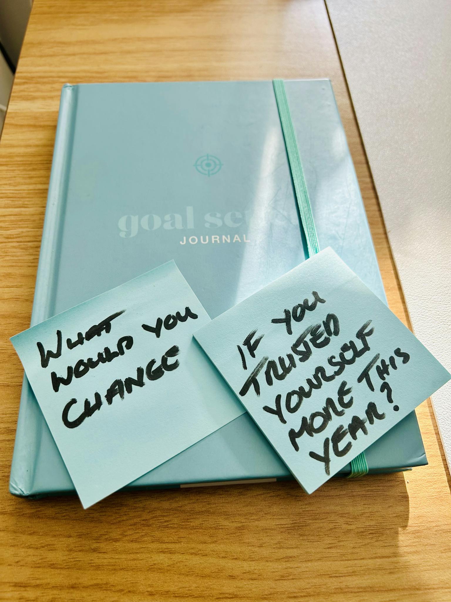 A teal goal setting journal with motivational sticky notes prompting reflection and self-trust.