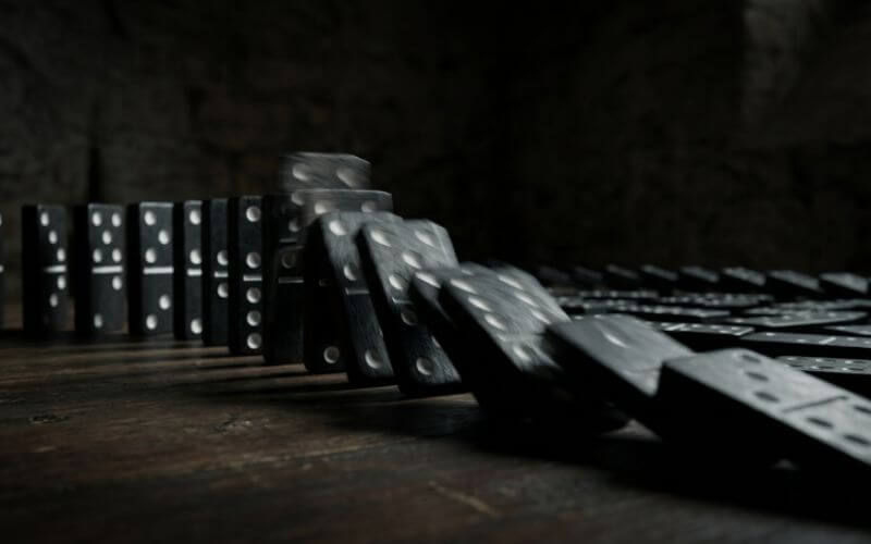 dominoes falling in chain reaction representing habit stacking to build consistency habits step by step